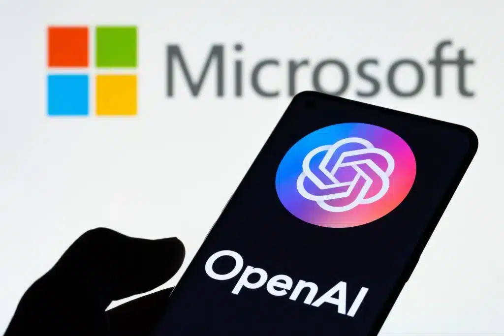 Microsoft logo in the background and OpenAI logo on a cellphone in the front.